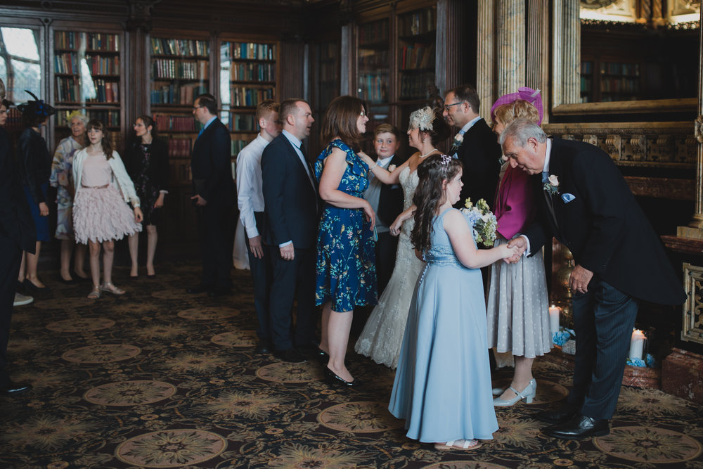  Documentary approach to photographing the receiving line at Crewe Hall in Cheshire. A bridesmaid is welcomed by the groom's father. 