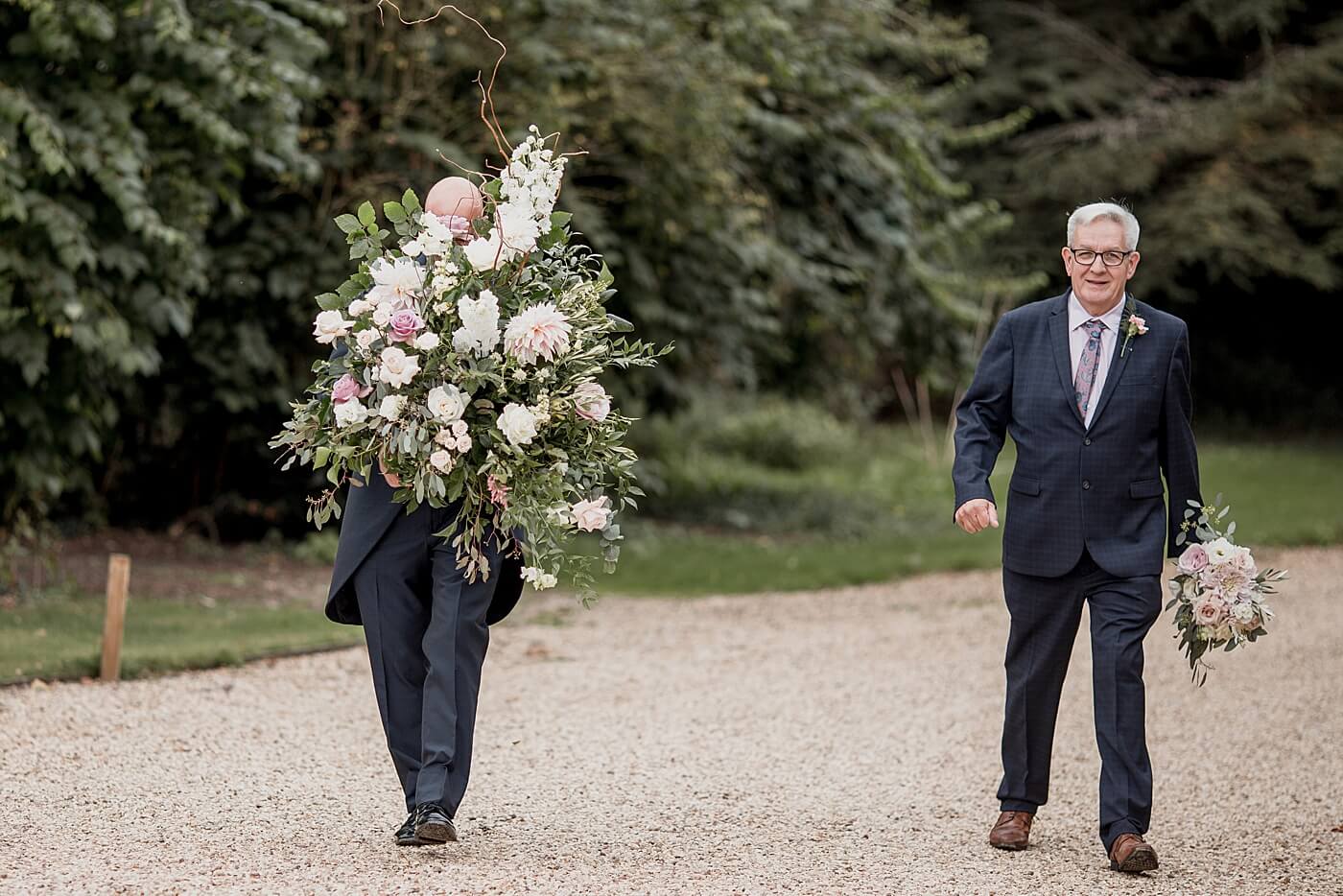 groomsmen carrying flower arrangement