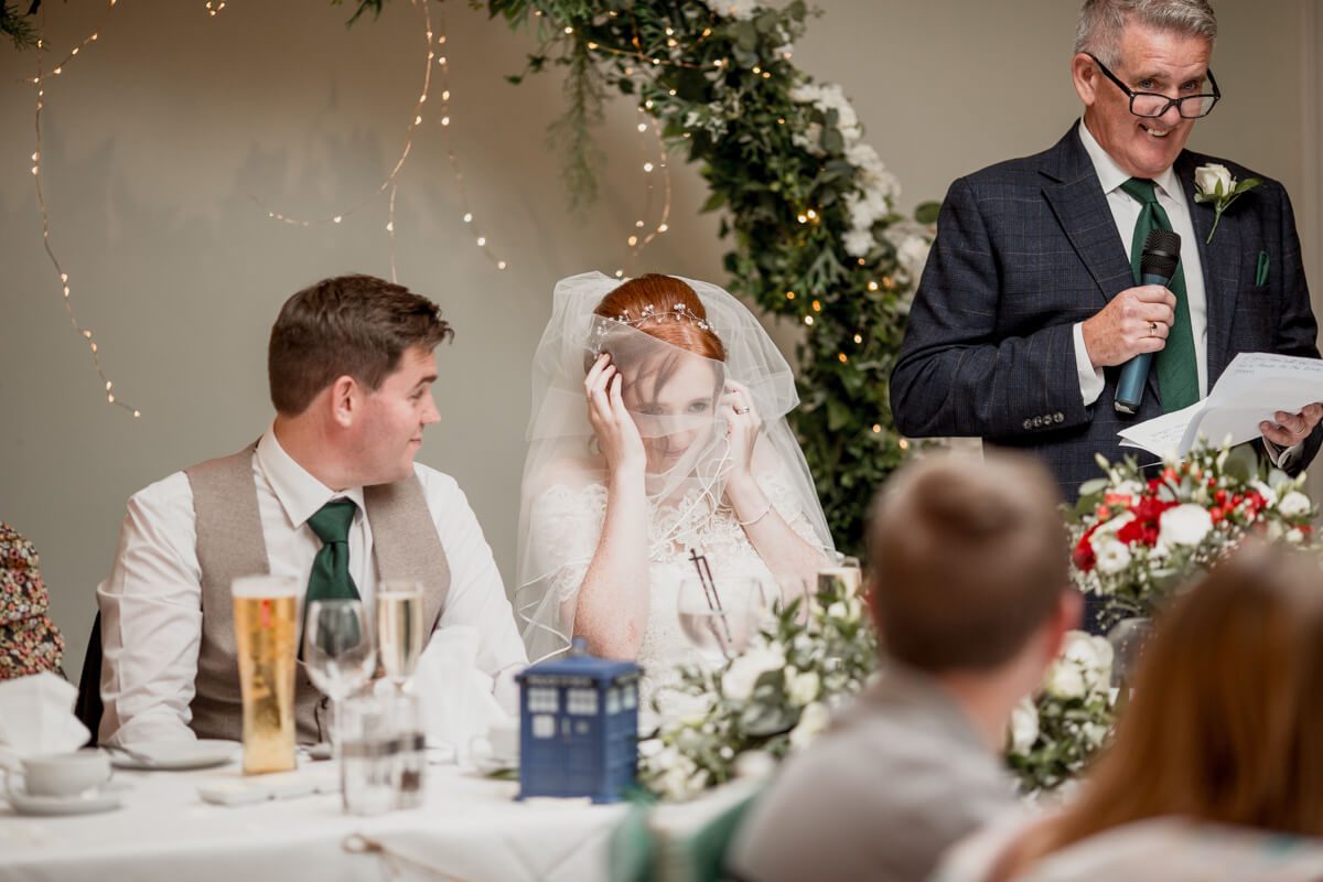 bride covers her face during speeches