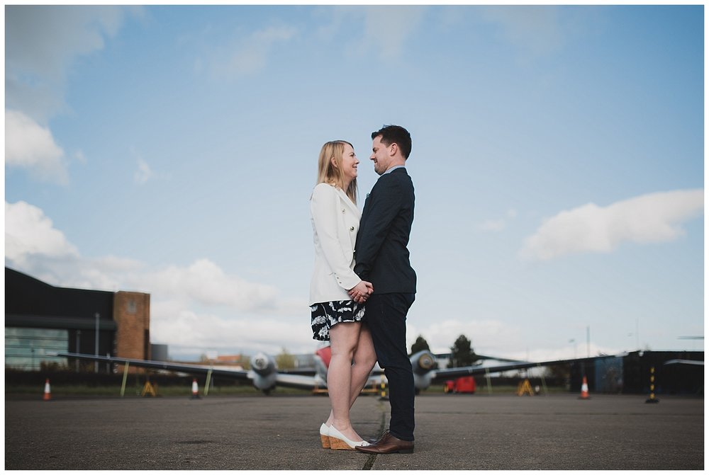  Engaged couple on old runway with plane in the background. 
