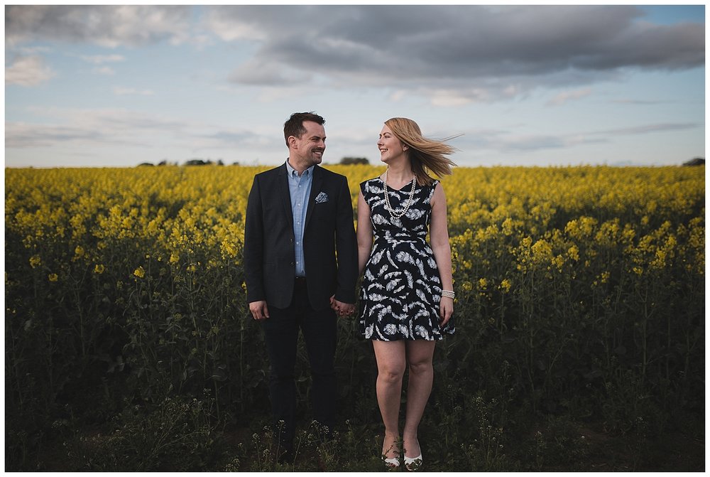  Engaged couple with a field of yellow rapeseed flowers. 